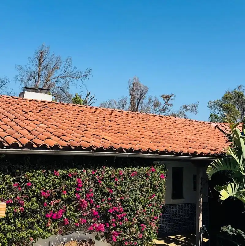 Finished clay tile roof on a white stucco Los Angeles home with bougainvillea along the wall