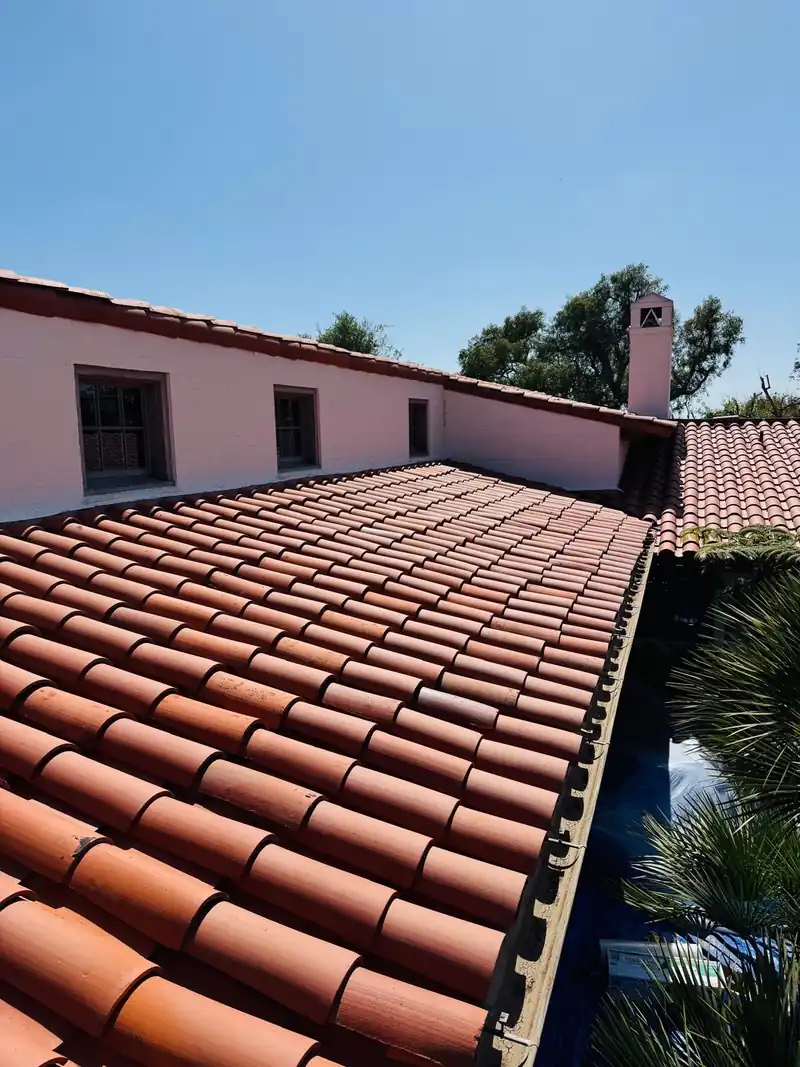Long run of red clay barrel tile along a Spanish style house with pink stucco walls
