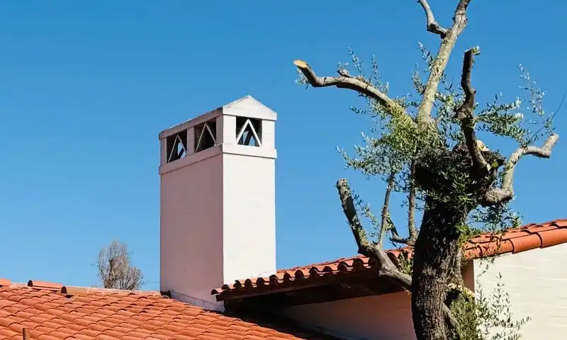 Clay tile roof meeting a white stucco chimney, where the flashing work keeps water out