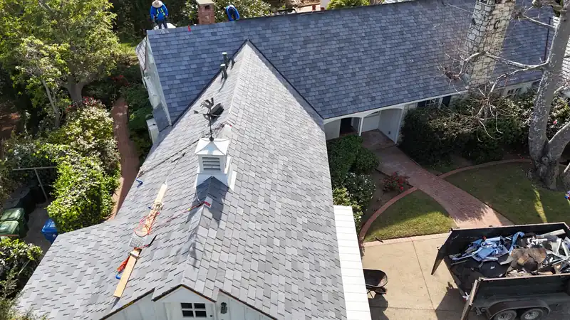 DaVinci composite slate-look tile going onto a house, with crew at the ridge and a cupola on the roof