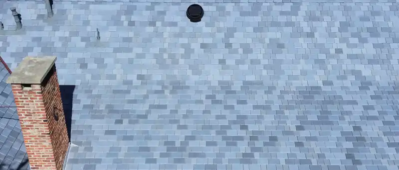 Composite slate laid in a mixed blend of light and dark grays, with a brick chimney