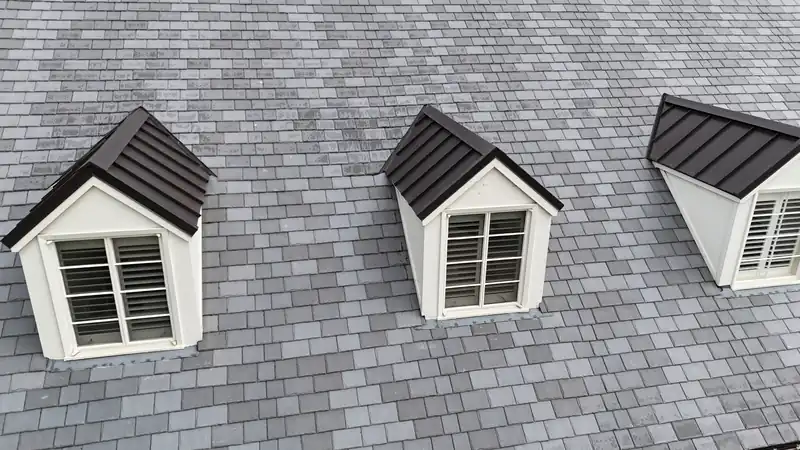 DaVinci composite slate in a blend of grays around three dormers with dark metal roofs