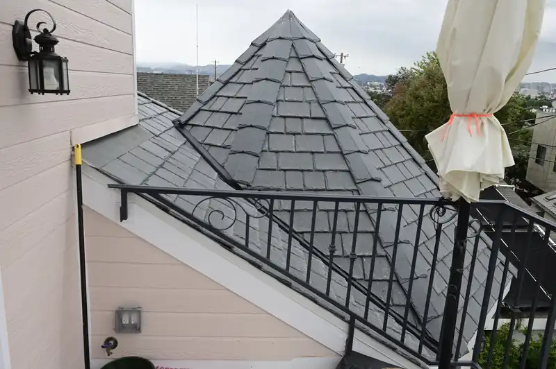 Slate-look composite tile on a turret roof beside a balcony