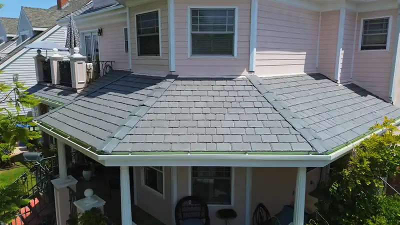 Slate-look composite tile on a hipped porch roof of a pink two-story house