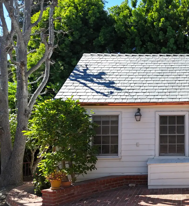 Gray slate-look composite roof above a cream board-and-batten house with a lantern by the window