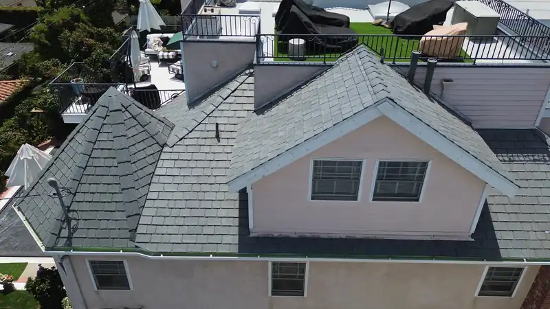 Slate-look composite roof with hips and dormers on a pink multi-story Los Angeles home