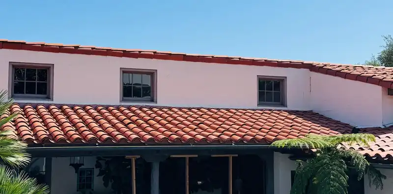 Two-story white stucco house with clay barrel tile on the porch roof and the main roof
