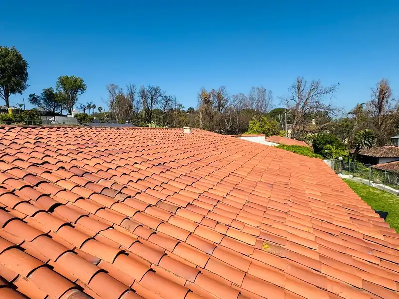 Field of red clay barrel tile on a single-story roof under a clear sky