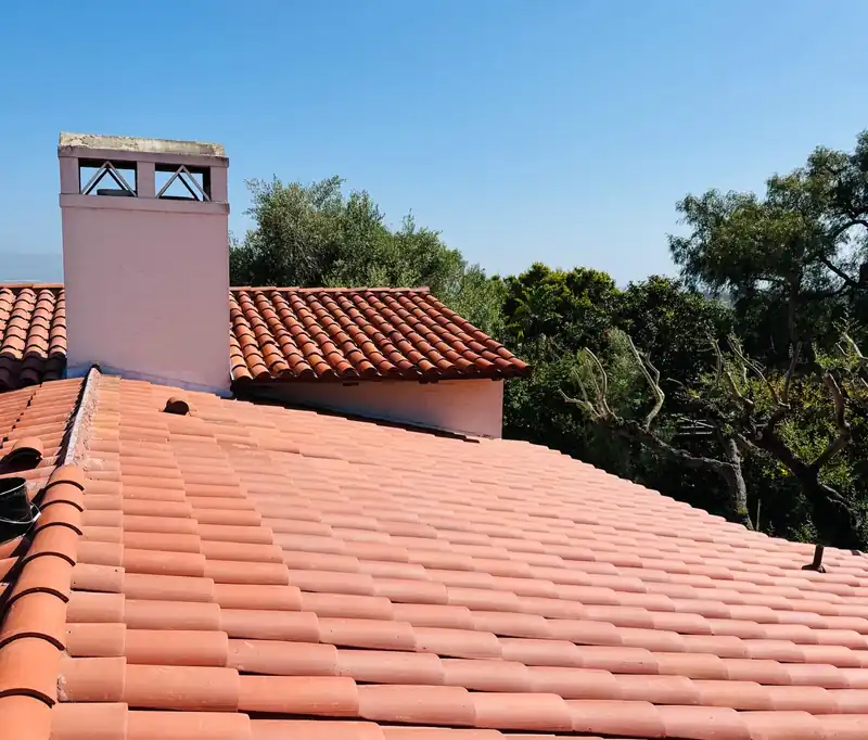 Even courses of new clay barrel tile running up to a white stucco chimney